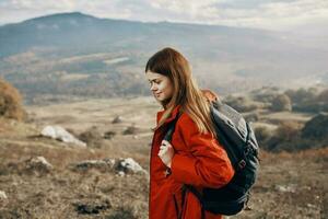roodharig vrouw in jasje met rugzak reizen wandelen bergen vers lucht foto