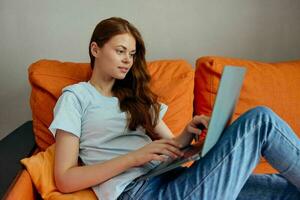 vrouw gebruik makend van laptop zittend Aan de bankstel ongewijzigd foto