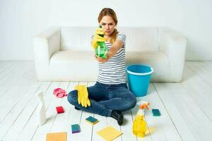 vrouw zittend Aan de verdieping met schoonmaak benodigdheden schoonmaak onderhoud huiswerk foto