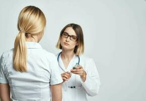 een verpleegster dokter in een medisch japon legt uit iets naar een geduldig in een wit t-shirt foto