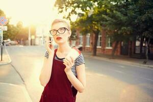 mooi vrouw met bril Aan de straat pratend Aan de telefoon in zomer foto