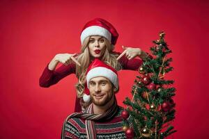 Mens en vrouw Kerstmis boom decoratie pret vakantie rood achtergrond foto