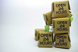 Open 24 uren tekst in klein dozen en boodschappen doen kar. concepten over online winkelen. geïsoleerd Aan wit achtergrond foto