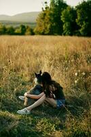 vrouw zittend in een veld- met een teckel hond glimlachen terwijl uitgeven tijd in natuur met een vriend hond in herfst Bij zonsondergang foto