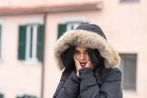 schattige jonge vrouw bevriezing in winterjas staande in straat foto