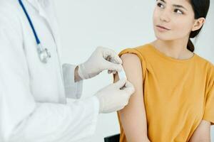 een dokter in beschermend handschoenen naar stok een injectie gips Aan een vrouw vaccinatie foto
