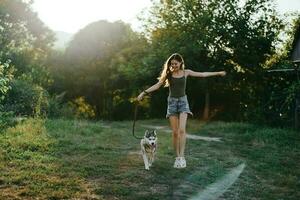 een vrouw loopt met een hond in de Woud gedurende een avond wandelen in de Woud Bij zonsondergang in herfst. levensstijl sport- opleiding met uw geliefde hond foto