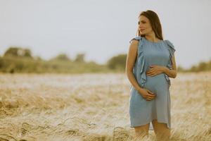 zwangere vrouw in blauwe jurk in een veld foto