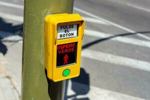 een groen verkeer signaal knop met inscripties in Spaans foto