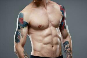 sportief Mens met gemotiveerd omhoog buikspieren bijgesneden visie van tatoeëren Aan armen detailopname foto