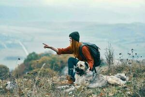 vrouw toerist met rugzak spelen met hond Aan natuur reizen foto