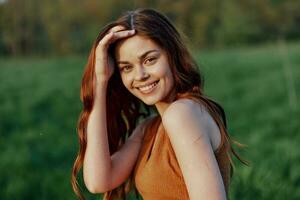 een jong vrouw lachend en glimlachen vrolijk in natuur in de park met de zonsondergang verlichting verhelderend haar lang rood haar- foto