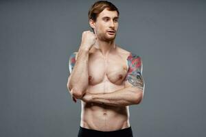 Mens met tatoeages Aan zijn armen gemotiveerd omhoog torso training bijgesneden visie bodybuilder foto