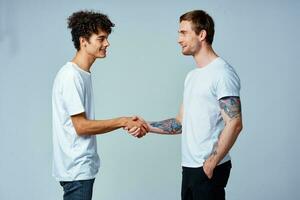 twee vrienden houden handen in wit t-shirts geïsoleerd achtergrond foto