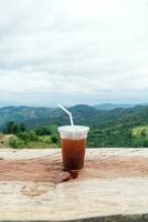 americano koffie Aan hout tafel met berg heuvel visie achtergrond foto