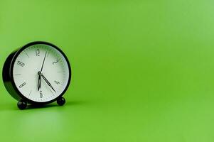 klok kostbaar tijd alarm klok Aan groen achtergrond concept van tijd werken met tijd foto