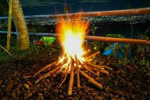 vreugdevuur en sommige vonken Aan de camping grond, met stad licht in de achtergrond foto