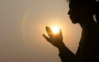 silhouet van trouw vrouw bidden Bij zonsondergang net zo concept voor geloof, vertrouwen, gebed en spiritualiteit. foto