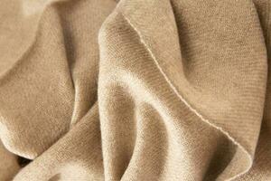 natuurlijk wol beige kleding stof. kasjmier, wol. structuur van natuurlijk wol kleding stof. breigoed. foto
