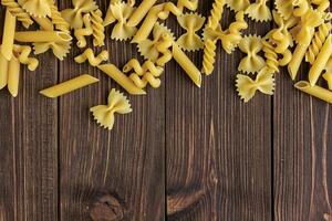 verschillend soorten van rauw pasta structuur met kopiëren ruimte Aan houten achtergrond. foto