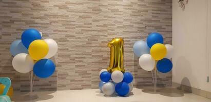 gemakkelijk eerste verjaardag jongen decoratie met aantal een ballon in goud kleur en ballonnen in geel, foto
