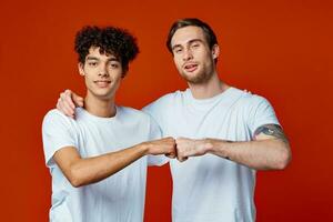 twee vrienden in wit t-shirts knuffels communicatie rood achtergrond foto
