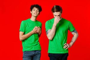 twee vrienden in groen t-shirts communicatie levensstijl rood achtergrond foto