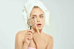 vrouw met een handdoek Aan haar hoofd Holding een vergroten glas in de buurt de gezicht hygiëne detailopname foto