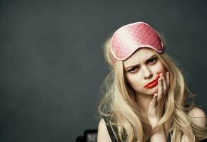 een blond met helder bedenken Aan haar gezicht en een roze slaap masker Aan haar hoofd foto