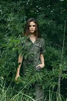 portret van een vrouw in de buurt de groen struiken, een jumpsuit is hand- in een zak- bladeren foto