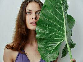 mooi vrouw in een zwempak Holding een groen blad in haar handen exotisch schoon huid foto