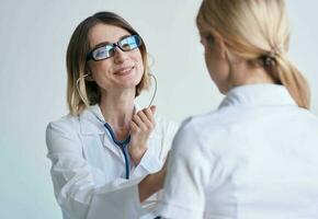 professioneel vrouw dokter in medisch japon en bril blauw stethoscoop geduldig foto