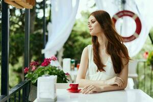 vrolijk vrouw in een wit jurk drankjes koffie buitenshuis in een cafe ontspanning concept foto