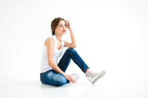 vrolijk meisje in een wit t-shirt en donkerblauwe spijkerbroek in de studio op een witte achtergrond foto