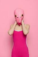 vrouw in een vis kostuum voor halloween poses tegen een roze achtergrond in een gek eng kostuum met een roze siliconen masker Aan haar hoofd foto