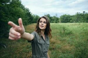 vrouw Aan natuur groen jumpsuit met uitgestrekt hand- shows een vinger foto