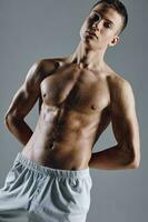 vent bodybuilder met gemotiveerd omhoog arm spieren Aan grijs achtergrond wit shorts bijgesneden visie detailopname foto