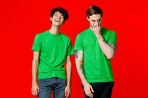 twee vrolijk vrienden in groen t-shirts vreugde van communicatie rood achtergrond foto