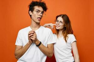 vrolijk jong paar in wit t-shirts samen vriendschap oranje achtergrond foto