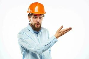 een Mens in een oranje helm overhemd bouw industrie werkte licht achtergrond foto
