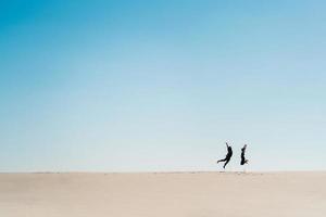 jong koppel een jongen en een meisje met vrolijke emoties in zwarte kleding lopen door de witte woestijn