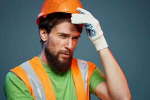 Mens in werk uniform oranje verf veiligheid werk vermoeidheid blauw achtergrond foto