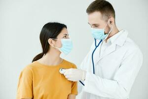 dokter in een medisch japon onderzoekt een vrouw geduldig in een blauw masker foto