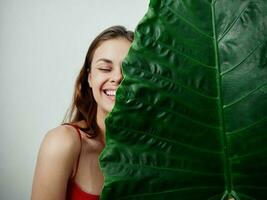 vrolijk vrouw Holding een palm blad in de buurt haar gezicht exotisch detailopname foto