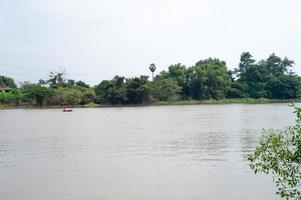 landschapsfoto van een visser die een boot roeit om te vissen in het midden van een rivier. foto