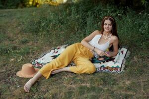 jong mooi hippie vrouw aan het liegen Aan de grond in natuur in de vallen in eco kleren in geel broek in de zonsondergang licht foto