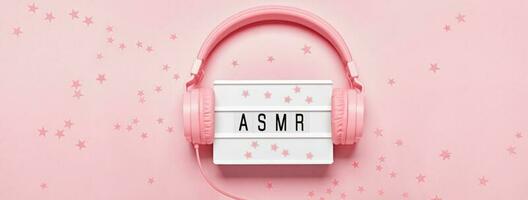 koptelefoon, asmr brieven lichtbak en confetti Aan roze spandoek. asmr stress verlichtend geluiden concept, vlak leggen, monochroom kleuren foto