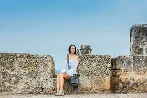 mooi vrouw Aan wit jurk zittend alleen Bij de muren omgeving de koloniaal stad van Cartagena de india's foto