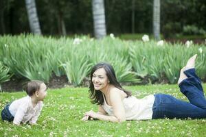 baby meisje spelen met haar mam Aan de gras foto