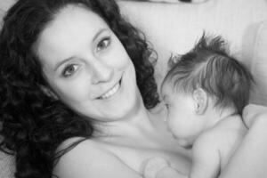 zwart en wit portret van een mooi jong moeder met haar een maand baby meisje foto